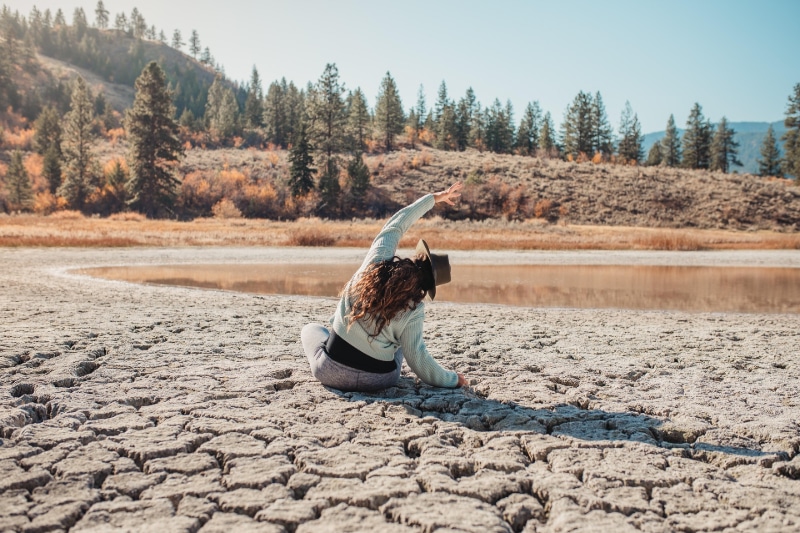 Person practicing mindfulness by meditating at a small lake surrounded by the rocky mountains